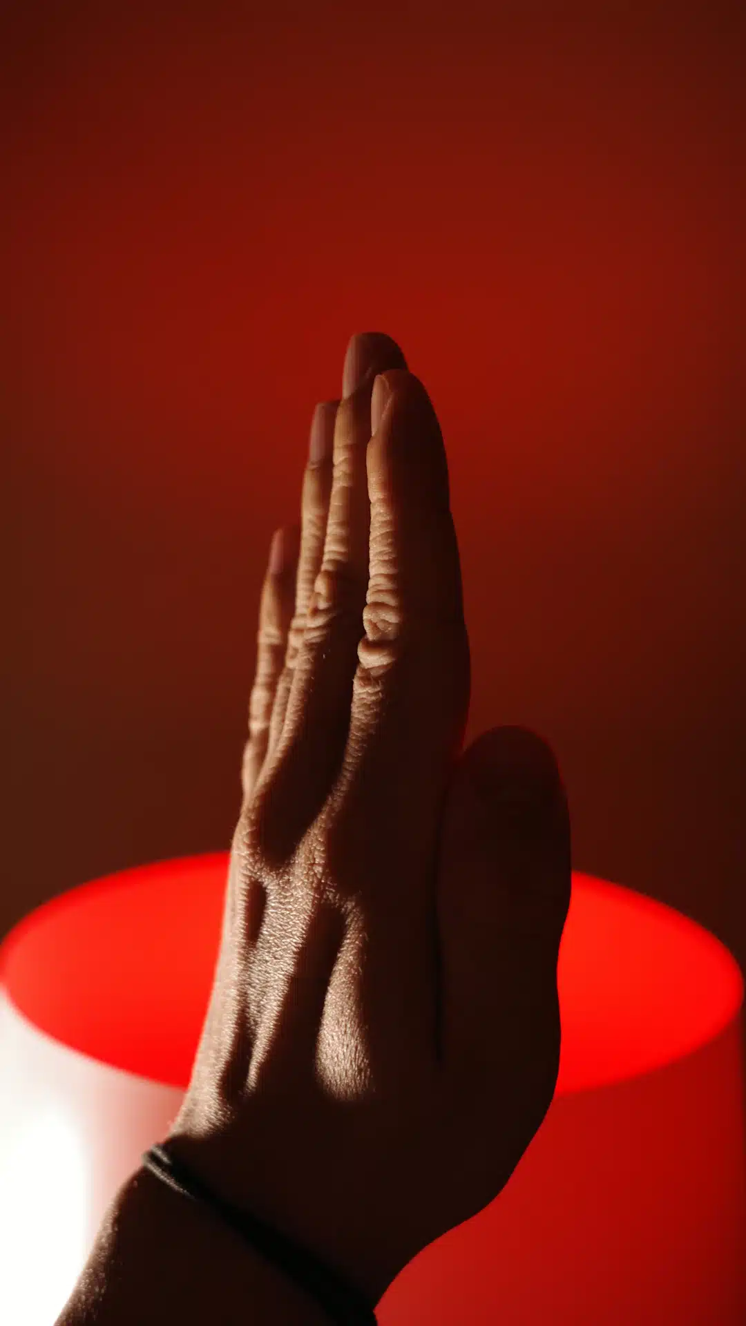 A person is holding their hands up in front of a lamp