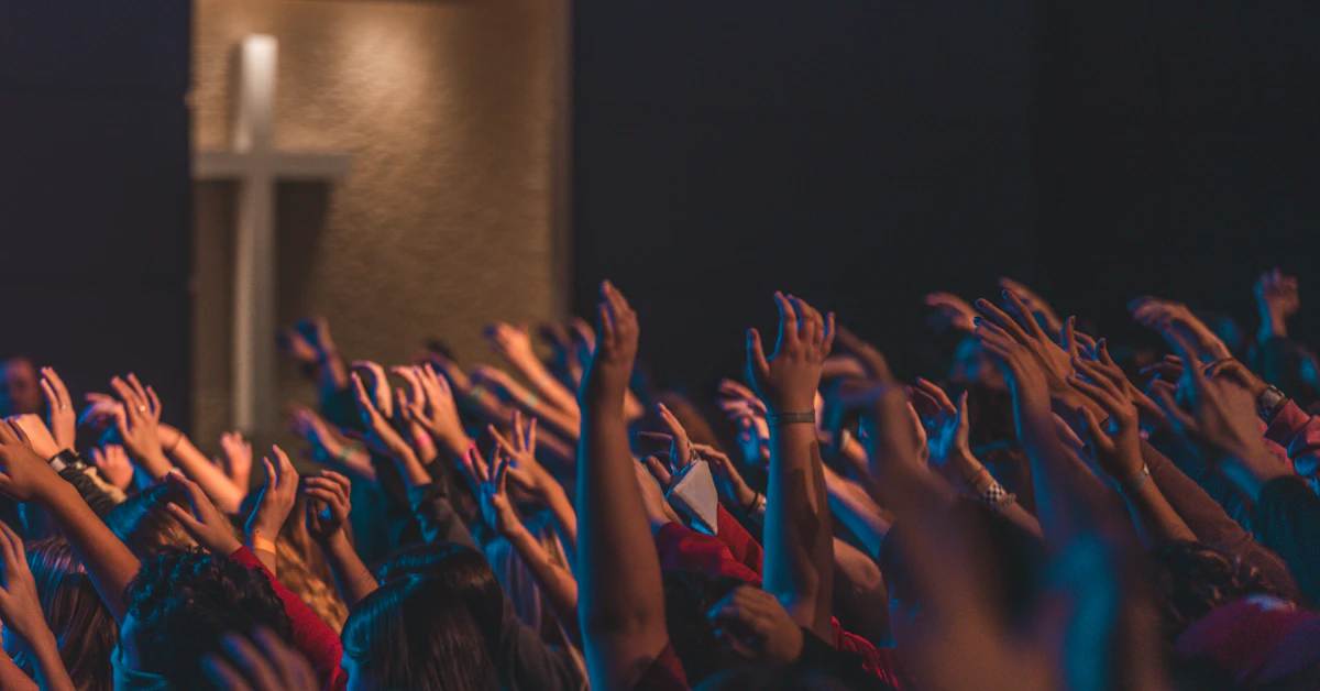 people raising their hands in front of stage