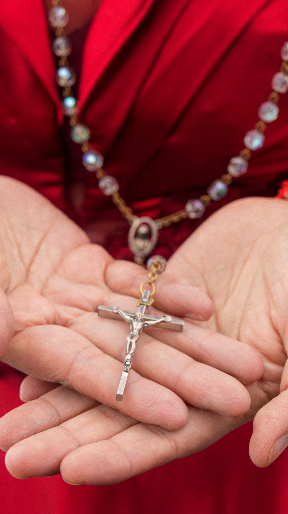 Close-up image of hands holding a rosary and crucifix, symbolizing faith and devotion.